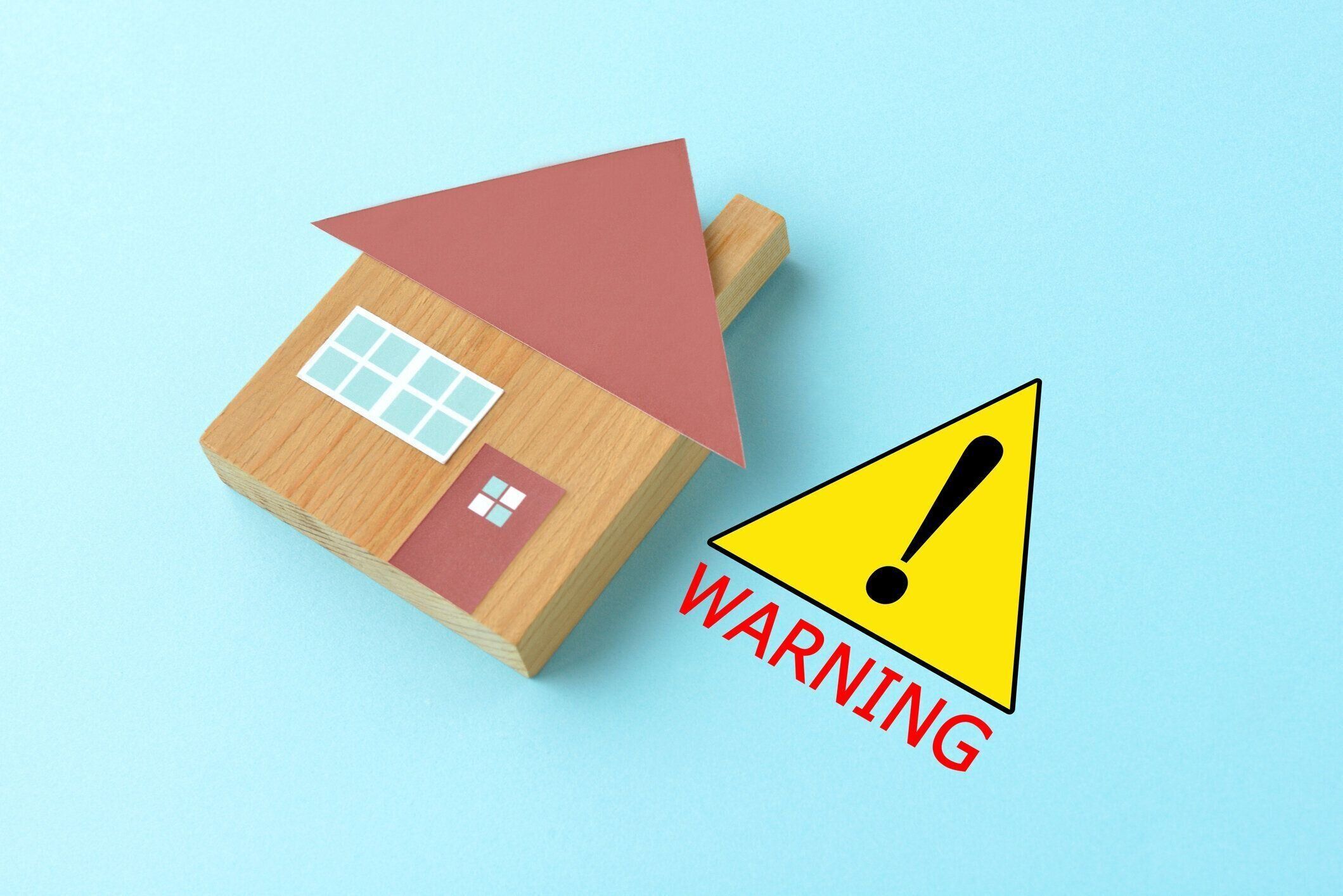 ライトブルーの背景に警告サインとハウスオブジェクト