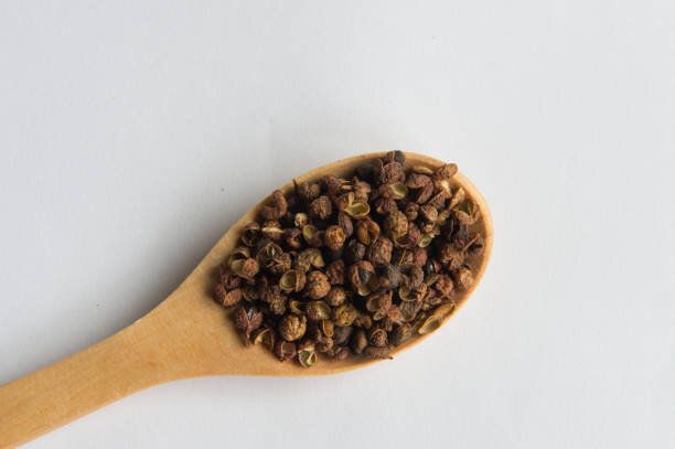 四川ペッパー ホワイト バック グラウンド (四川唐辛子) に分離された木製のスプーンで