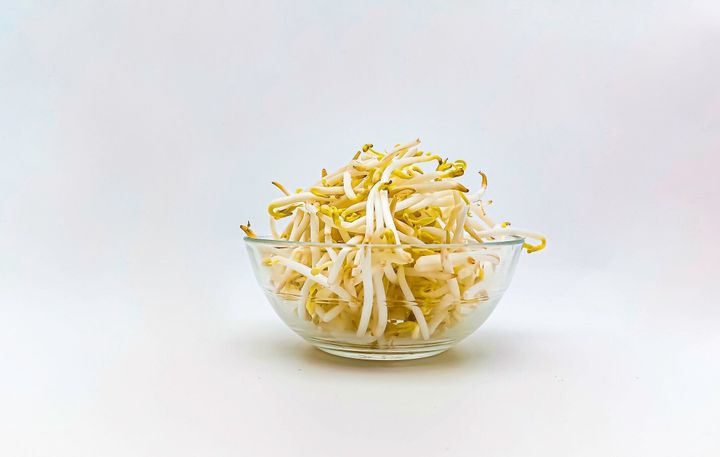 白い背景に透明なボウルにもやし。側面図。