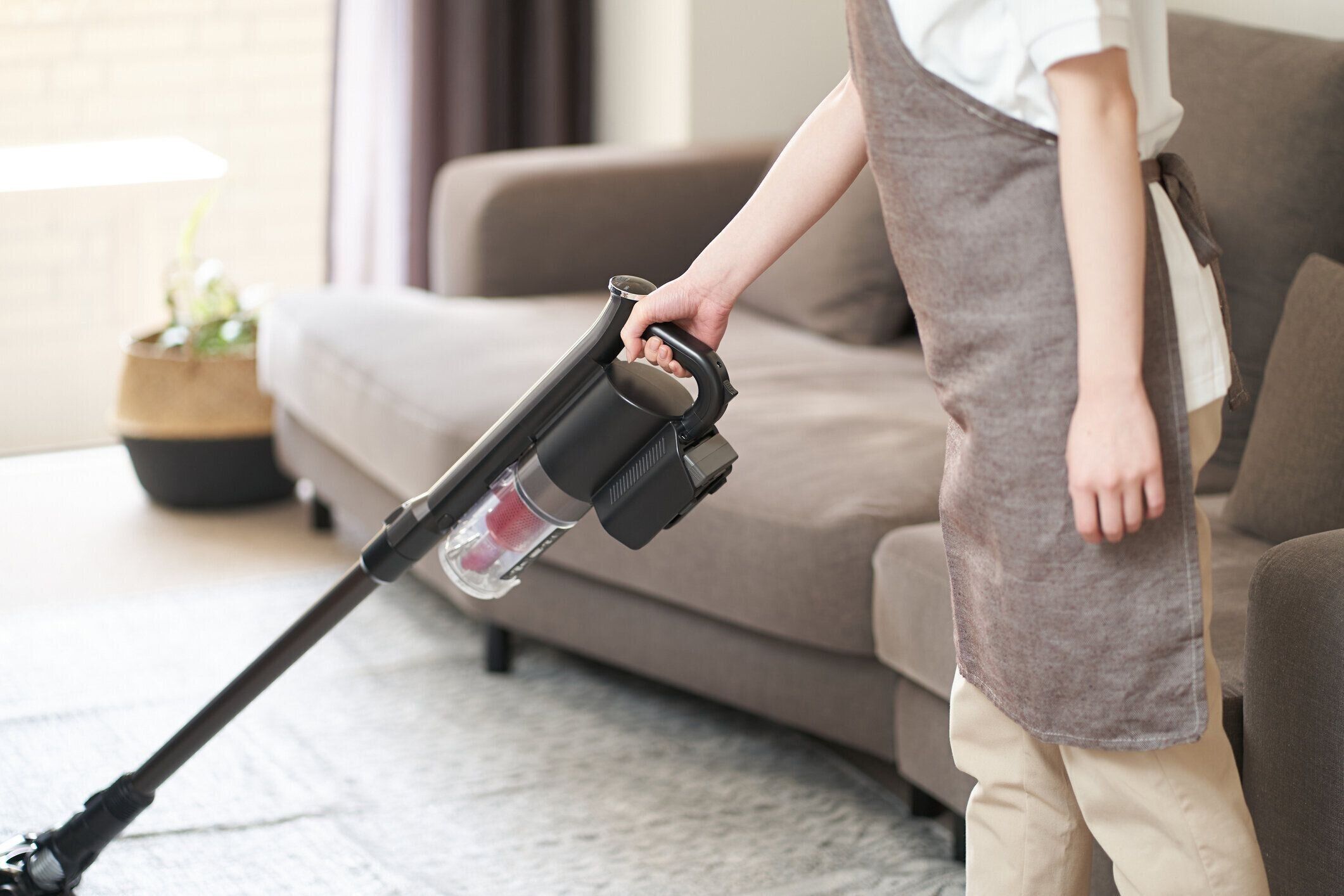 リビングルームで掃除機をかけるアジア人女性