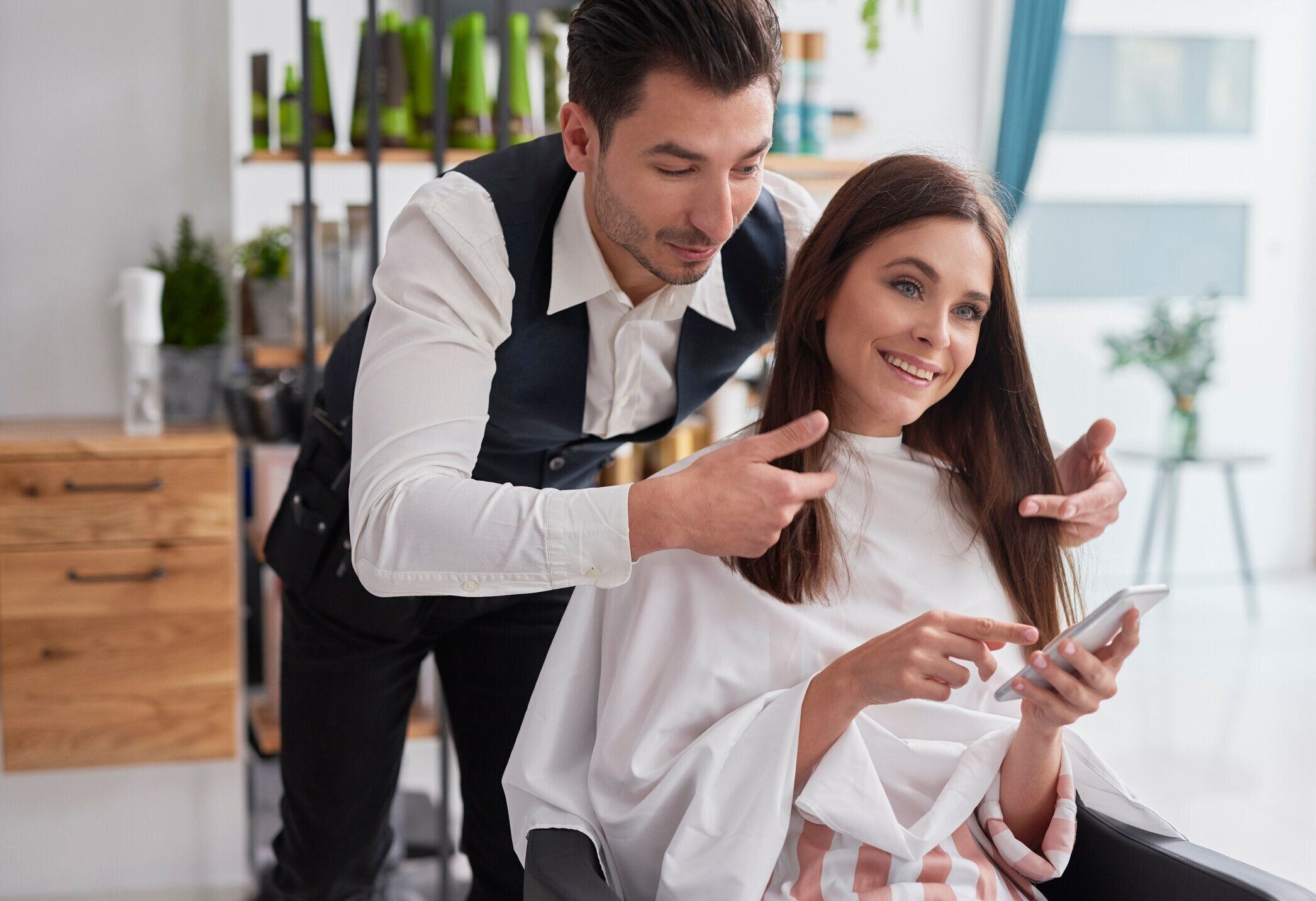 スマートフォンで自分が欲しい髪型を示す女性客