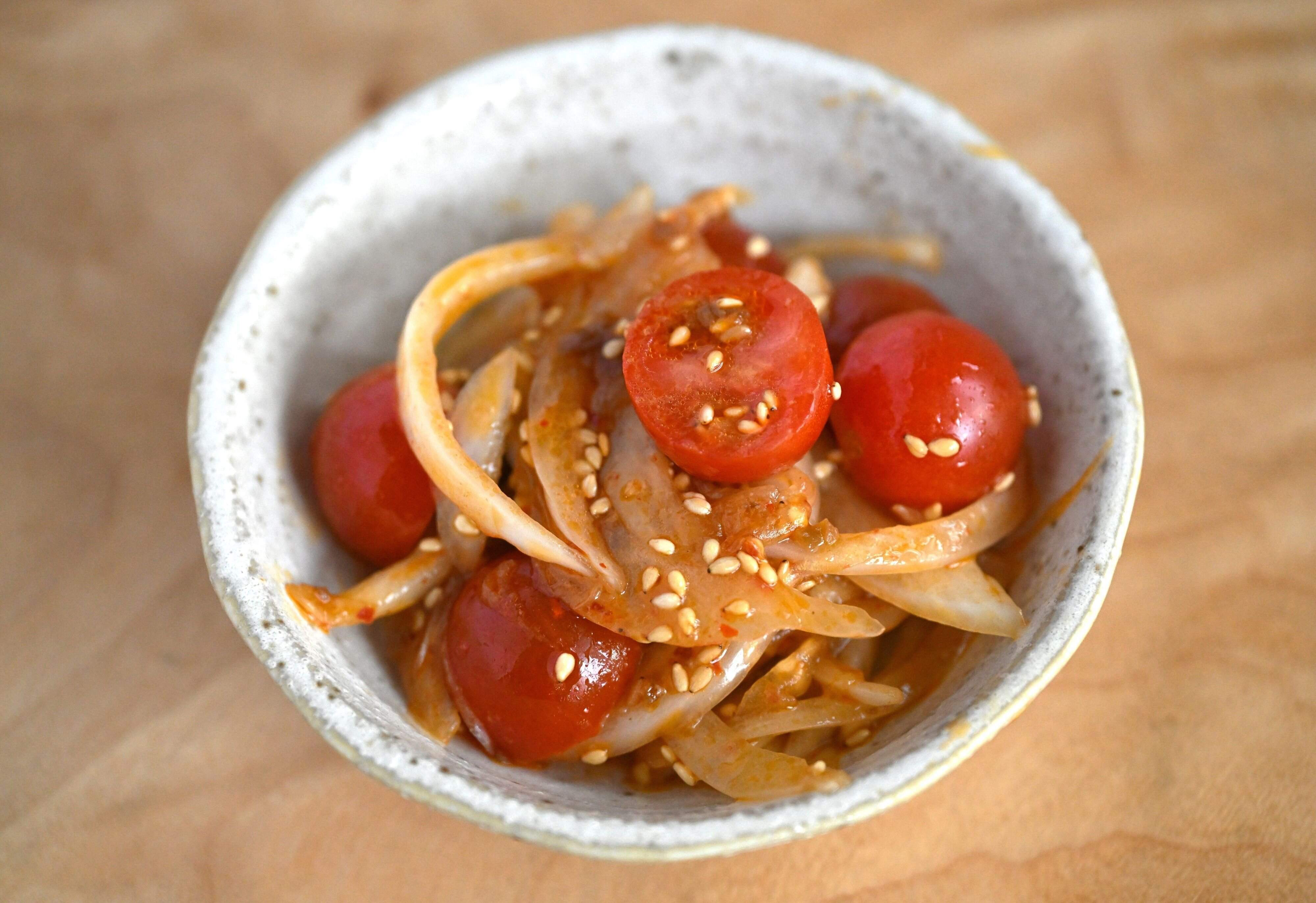 皿に盛られたミニトマトと新玉ねぎの坦担サラダ