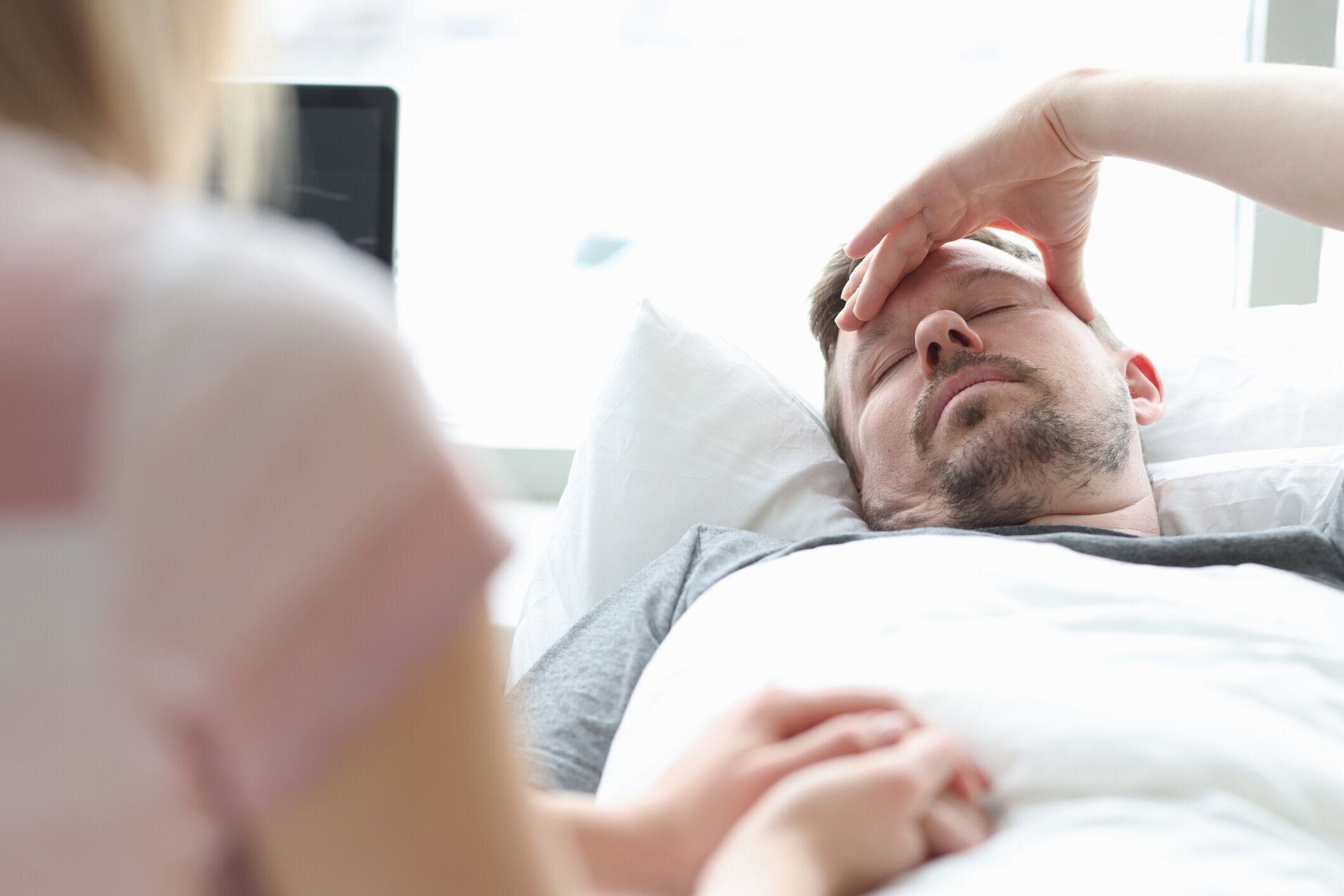 病室で病気の男性の手を握る女性の訪問者