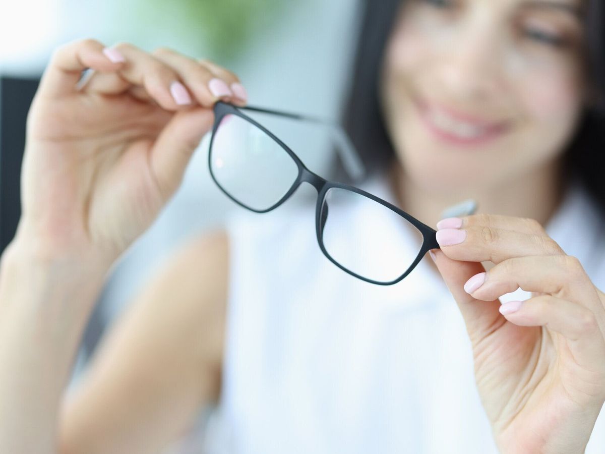 若い女性は手にビジョンのための黒い眼鏡を保持しています