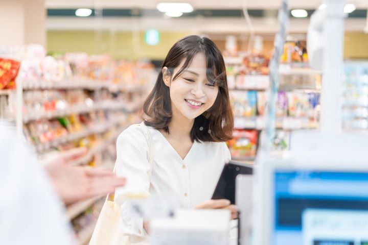 セルフチェックアウトと電子マネーの支払いを使用して若い女性