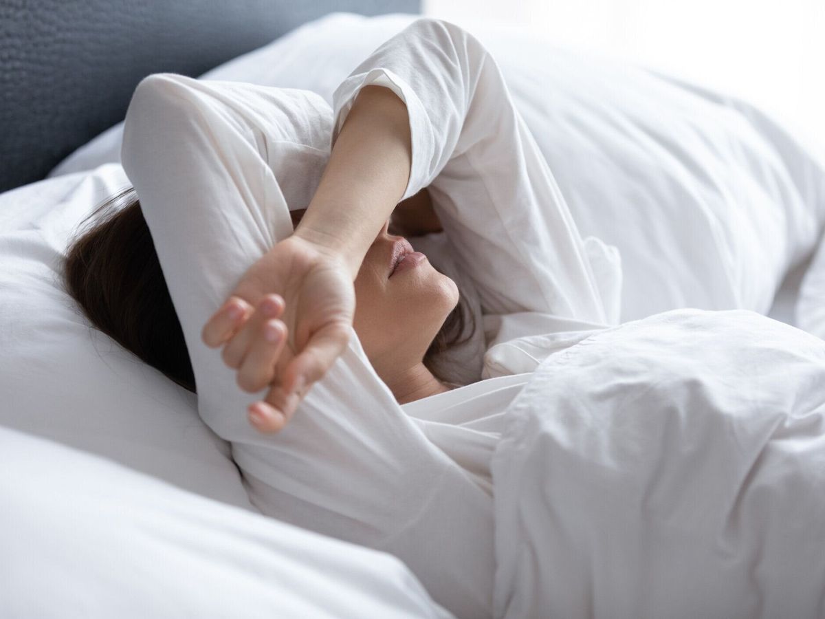 不眠症に苦しむ眠れない若い女性、手で目を覆う