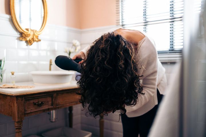 ヘアドライヤーで髪を乾かす若い女性