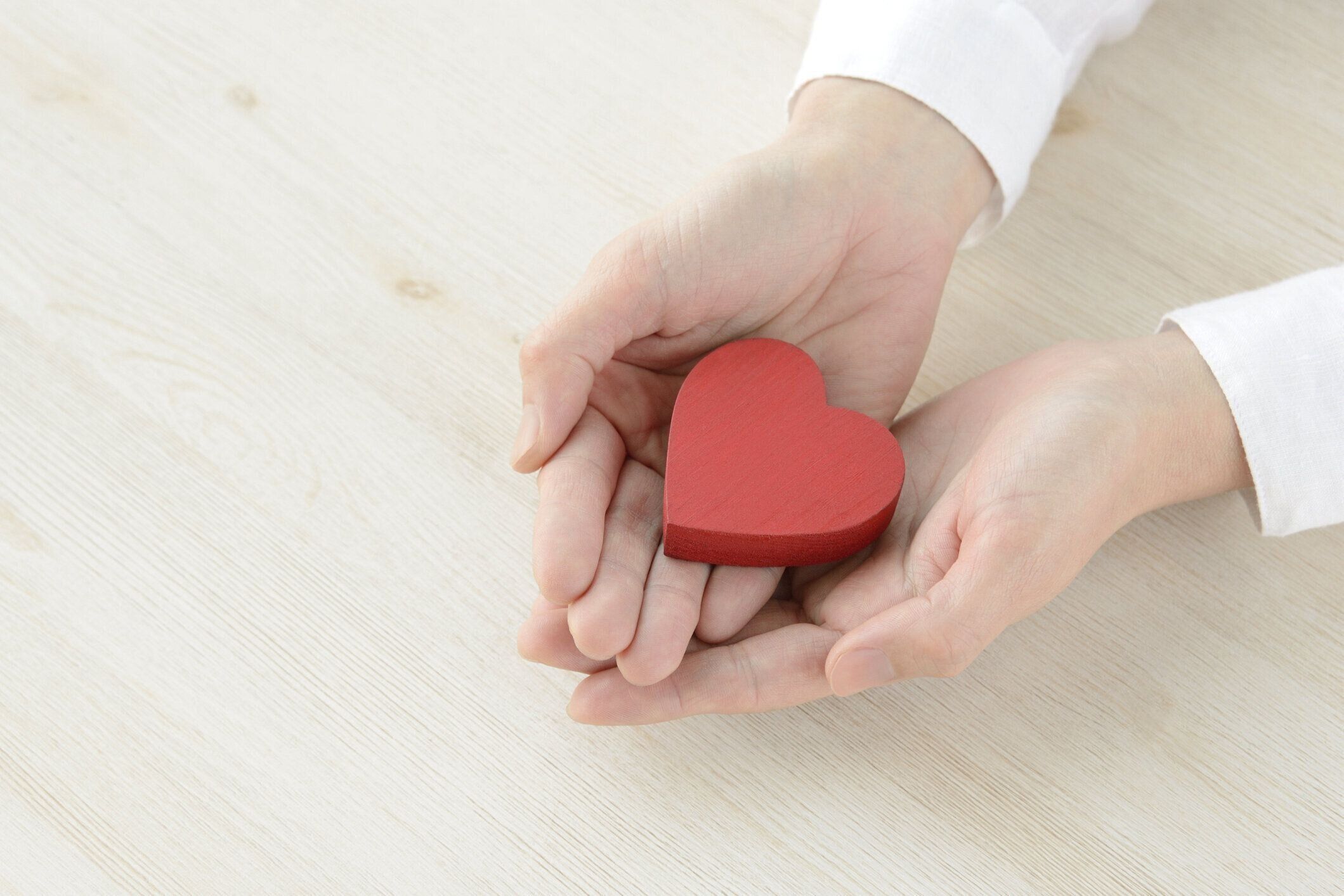 女性の手で覆われた心臓オブジェクト