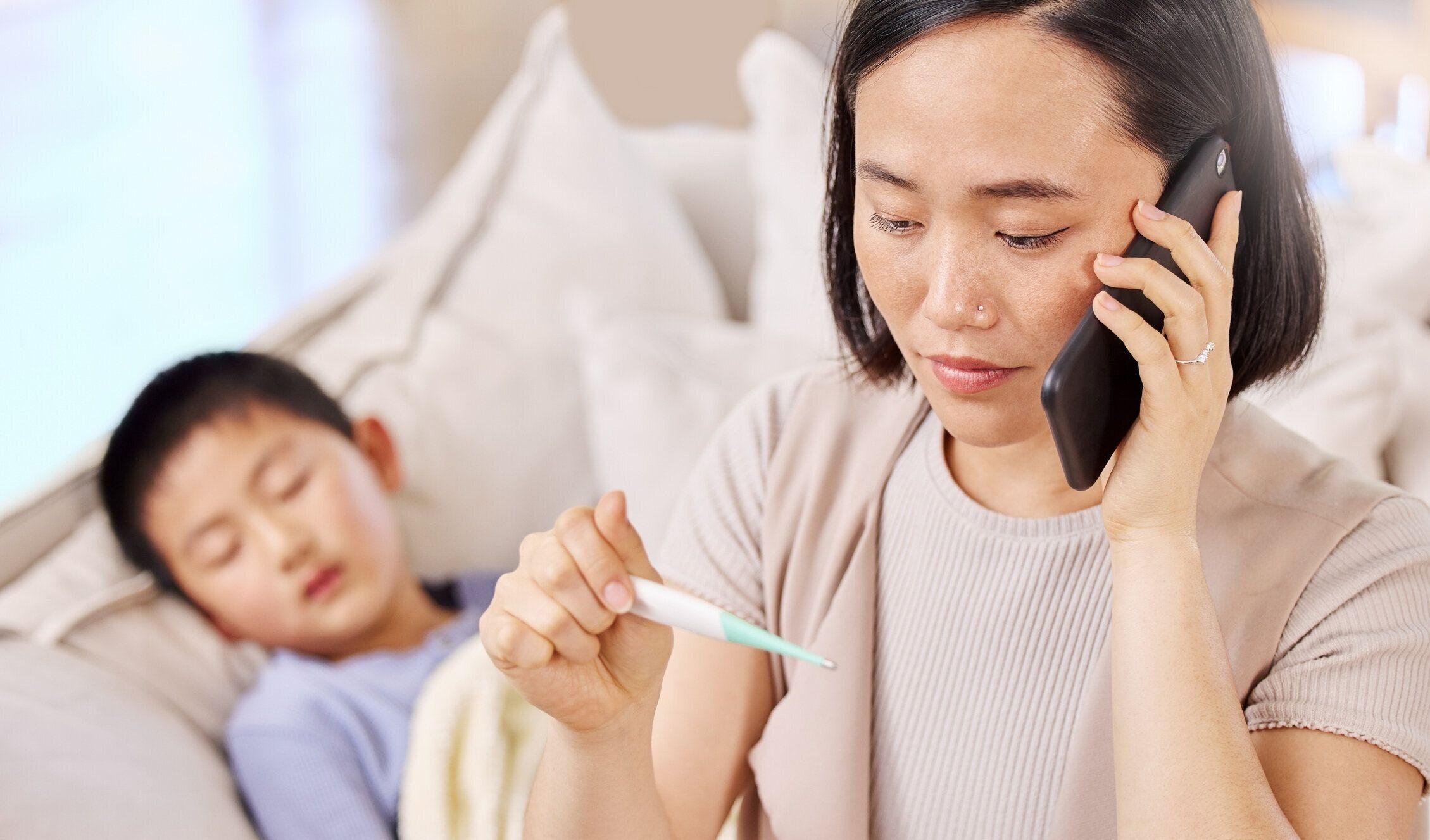 子供の体温を取った後、電話で話している女性のショット