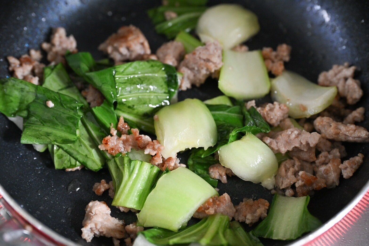 フライパンに入った炒めた豚ひき肉とちんげん菜