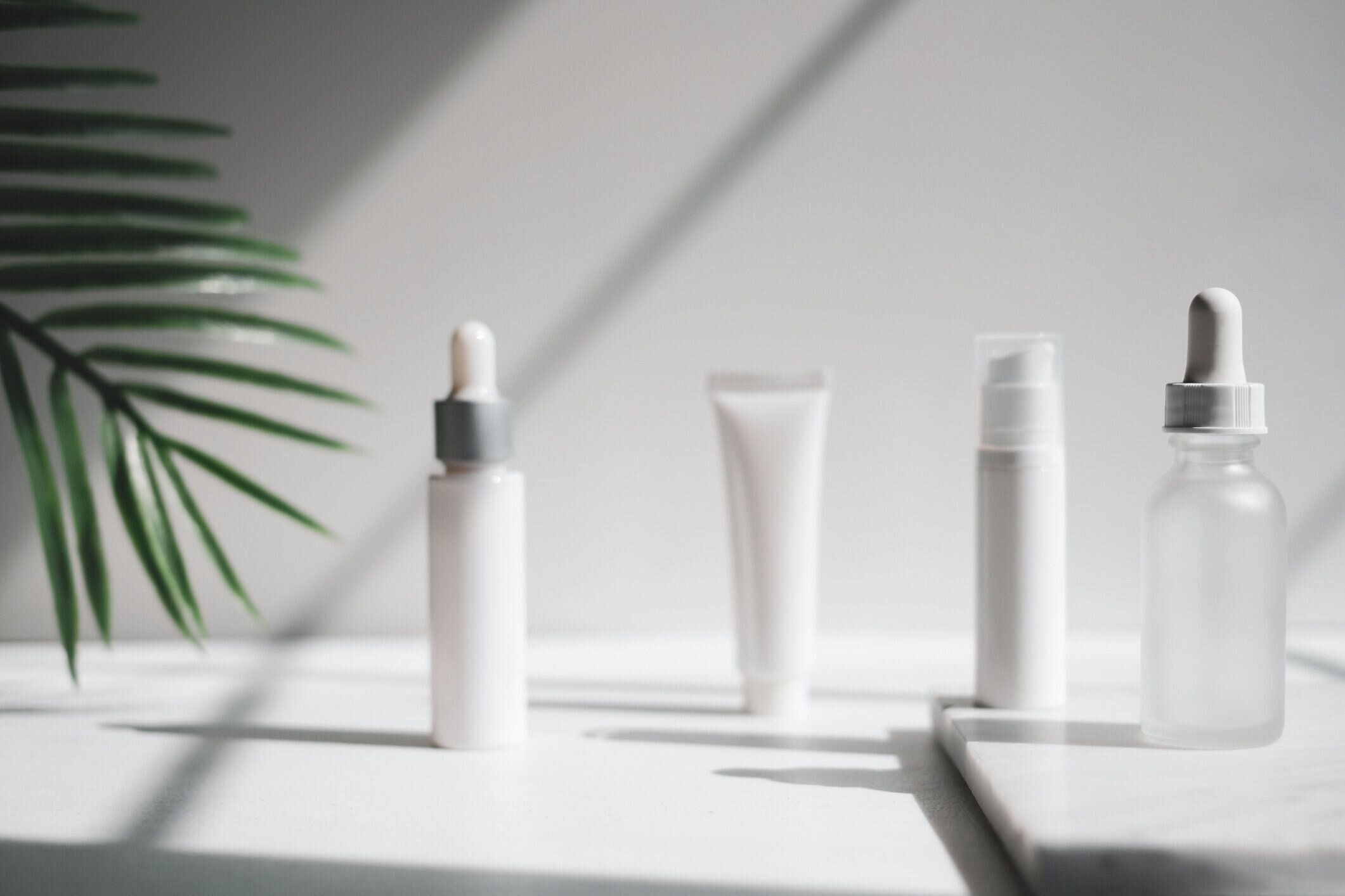 化粧品スキンケア包装.自然光と影を持つ豪華な白い大理石に美容製品モックアップ。