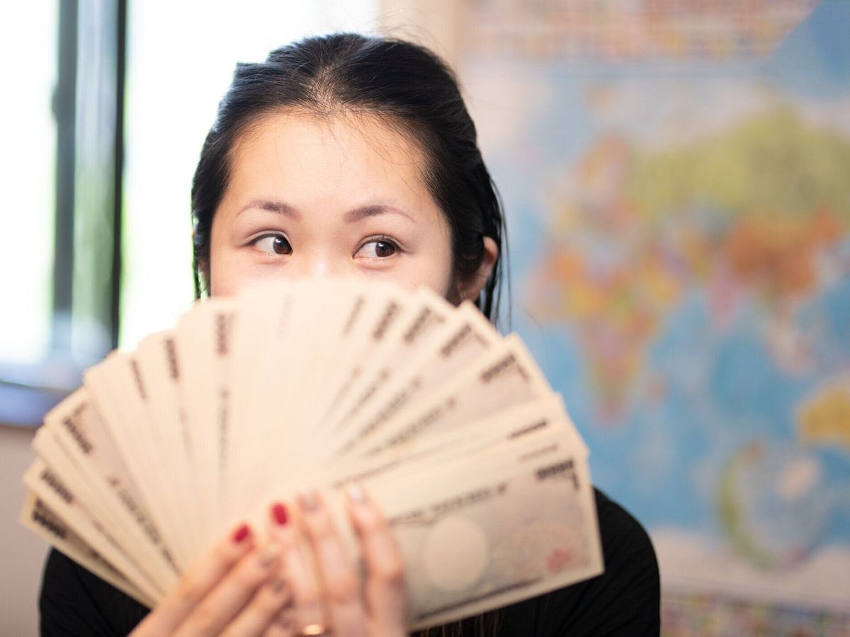 お金を数えて微笑む女性