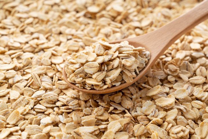 画面全体に置かれたオートミールの上に置かれた木製のスプーンをクローズアップします。