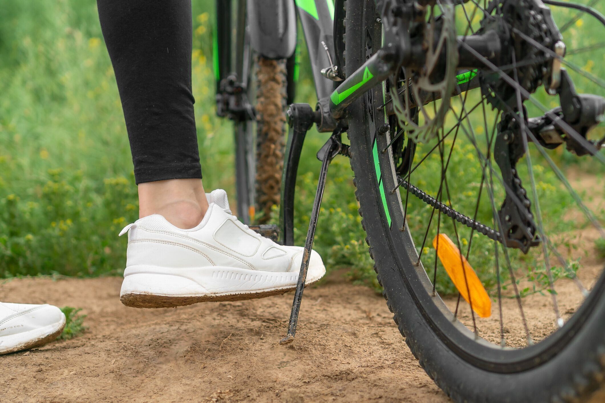 黒いレギンスと白いスニーカーを履いた女性の足のクローズアップがランニングボードから自転車を取り除く