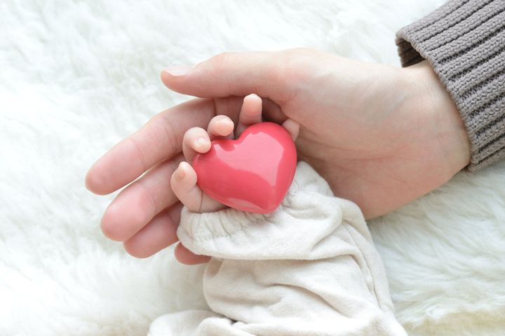 心臓の物体と母親の手を持つ赤ちゃんの手