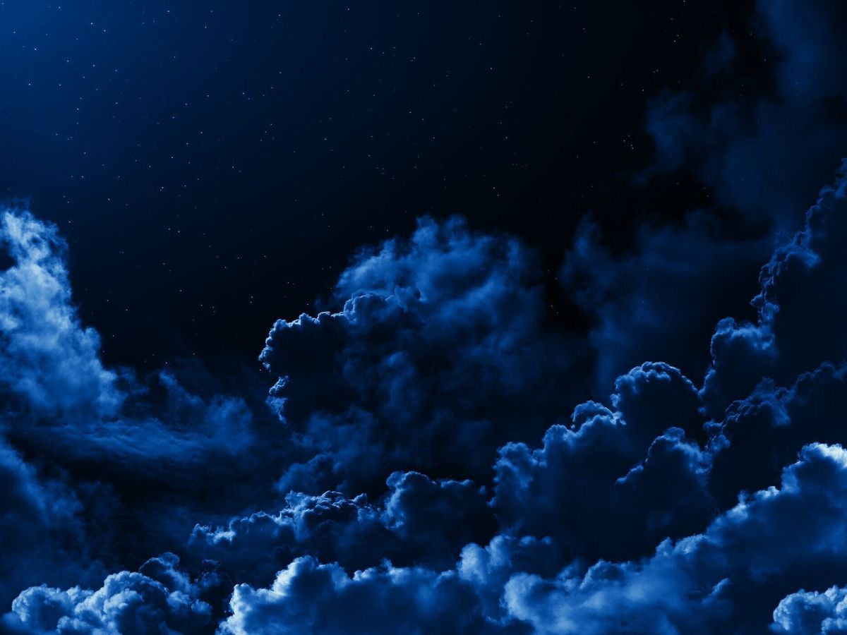 ドラマチックな雲に囲まれた星を持つ、神秘の真夜中の空。暗い自然の背景には夜の星空が曇っています。月明かりの雲