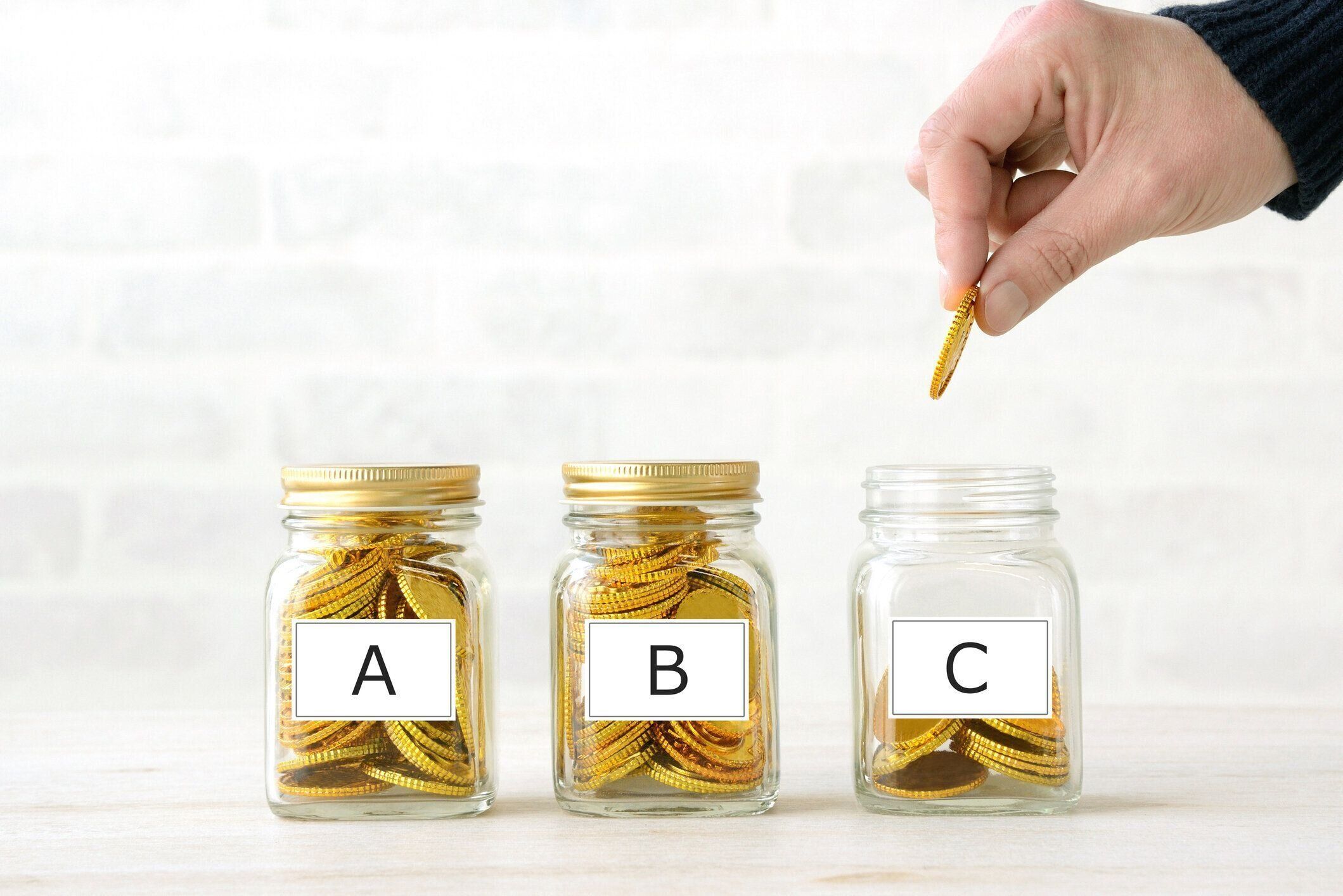 アルファベットの単語タグでボトルにお金を貯める人間の手