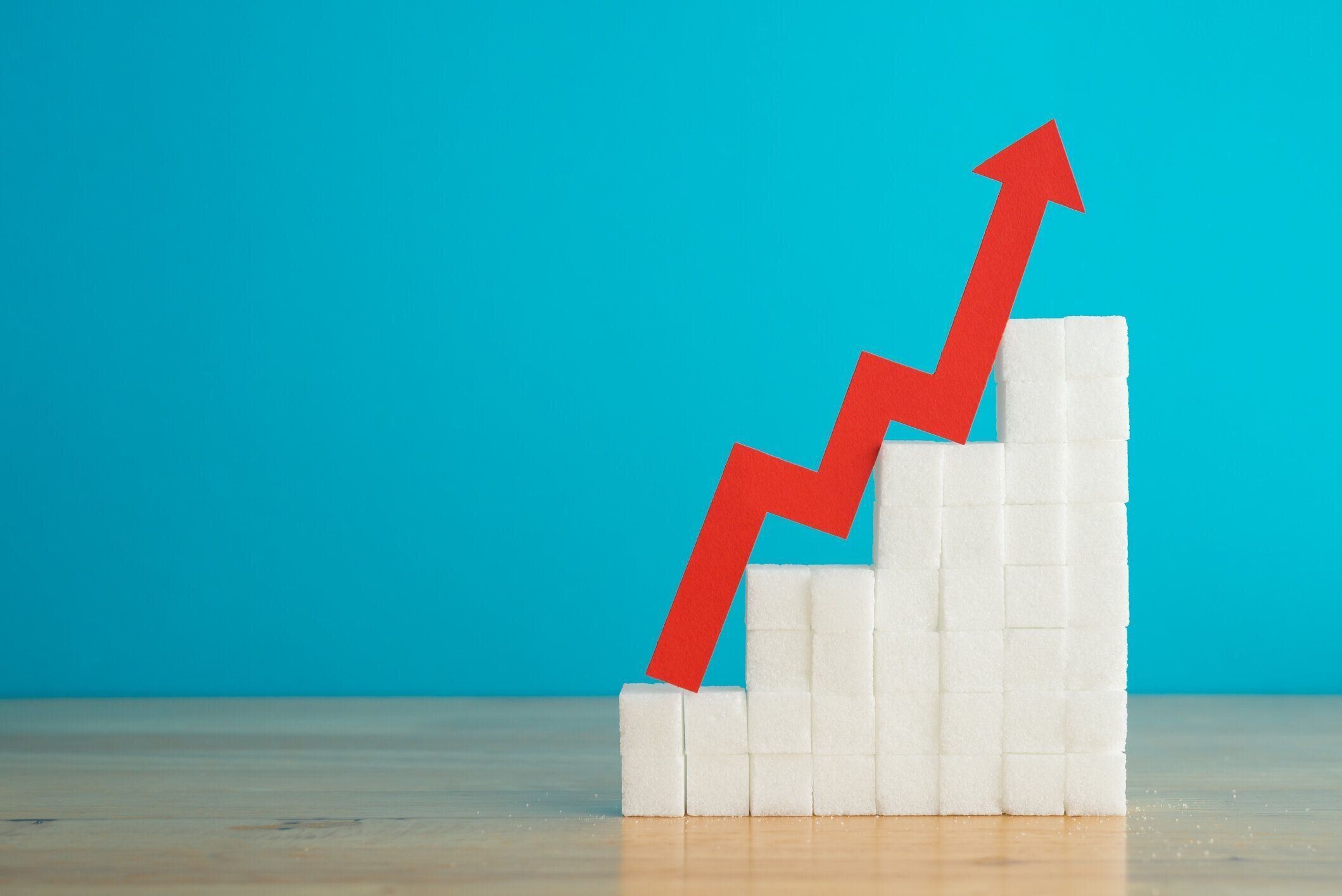 赤い矢印グラフは、青い壁の背景のコピースペースを持つスタック成長の角砂糖の上昇傾向です。