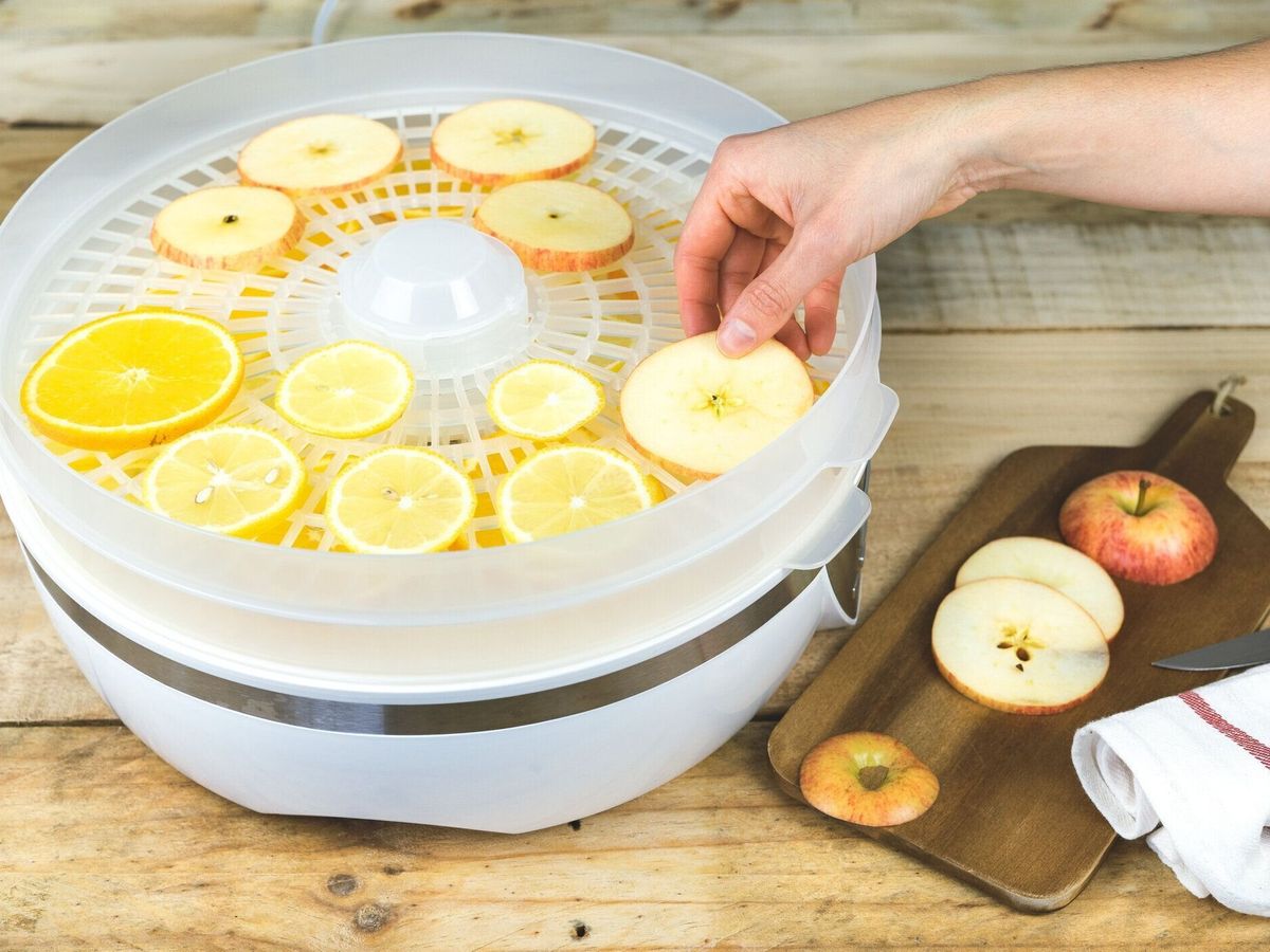 食品脱水機にフルーツスライスを置く手。缶詰。