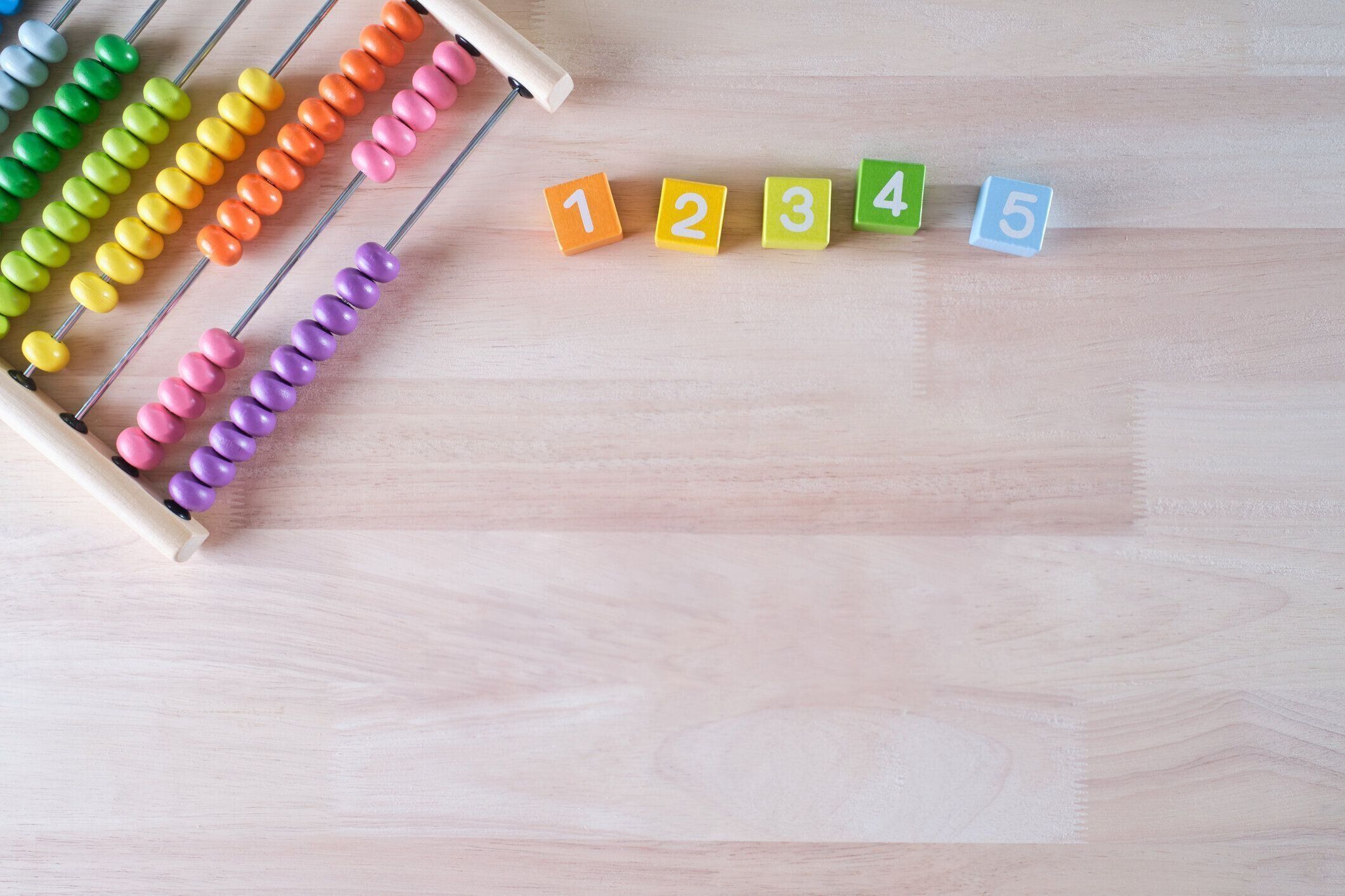 フラットレイ、明るい色の木製レンガとそろばんのおもちゃの背景のトップビューは、テキスト、子供の開発、初期の数学のスキルの概念のためのコピースペースを持っています