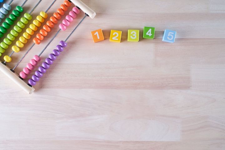 フラットレイ、明るい色の木製レンガとそろばんのおもちゃの背景のトップビューは、テキスト、子供の開発、初期の数学のスキルの概念のためのコピースペースを持っています