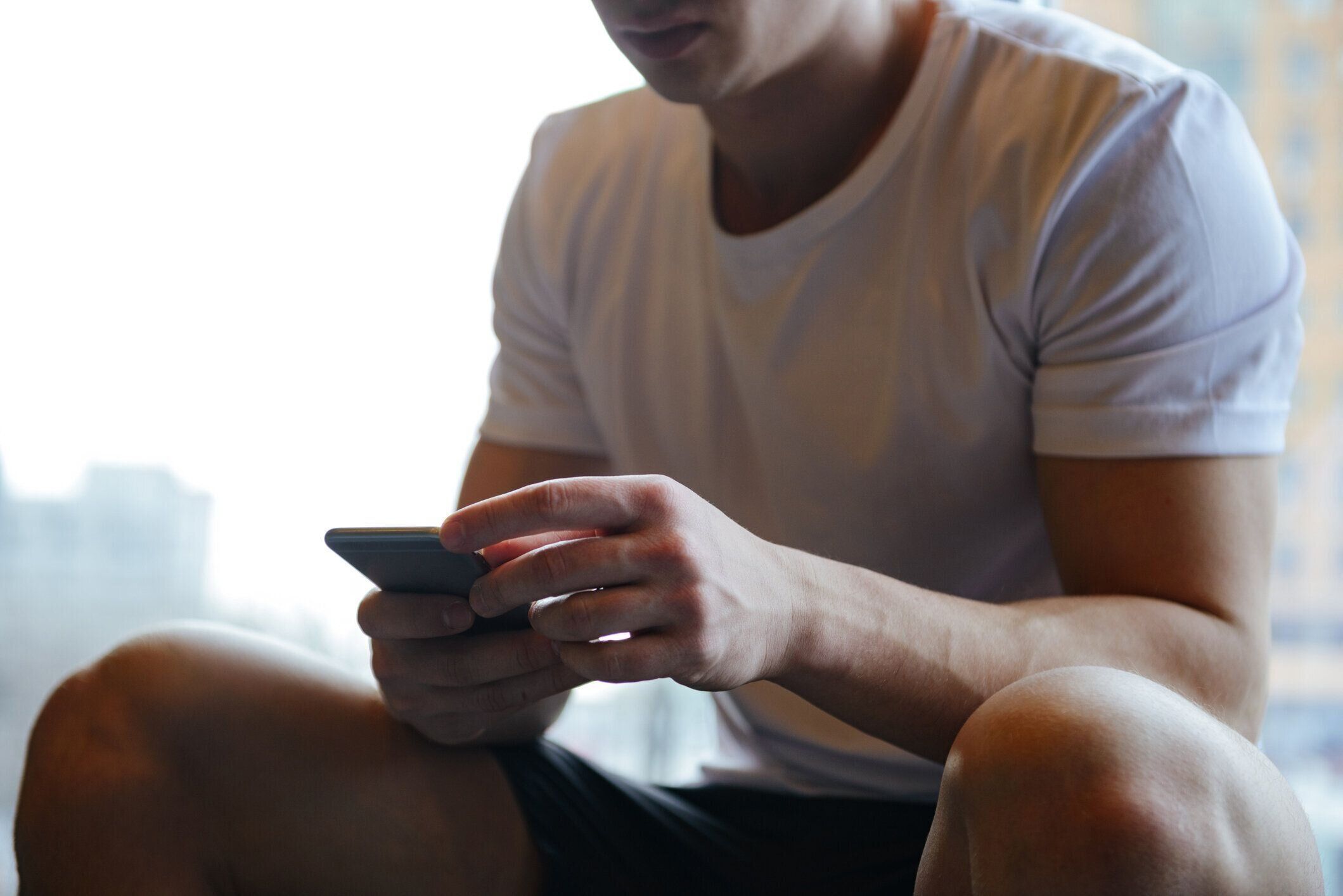 スマートフォンを使用した筋肉質男性のクロップド画像