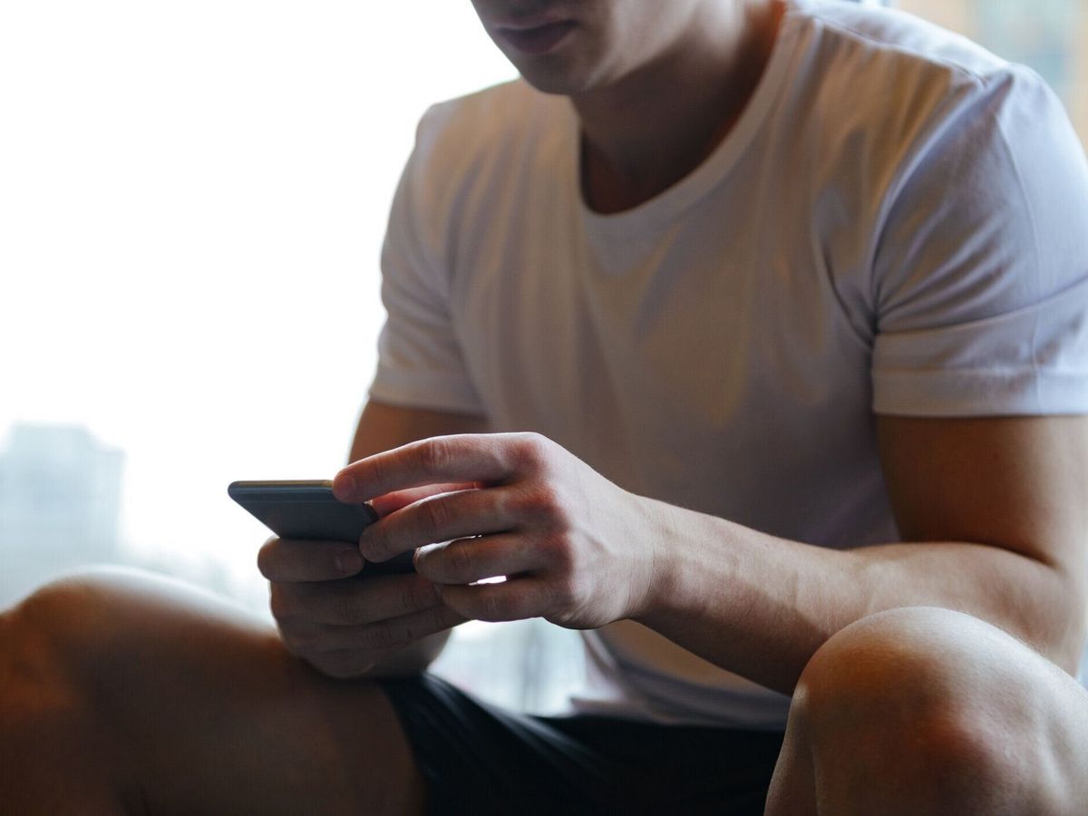 スマートフォンを使用した筋肉質男性のクロップド画像