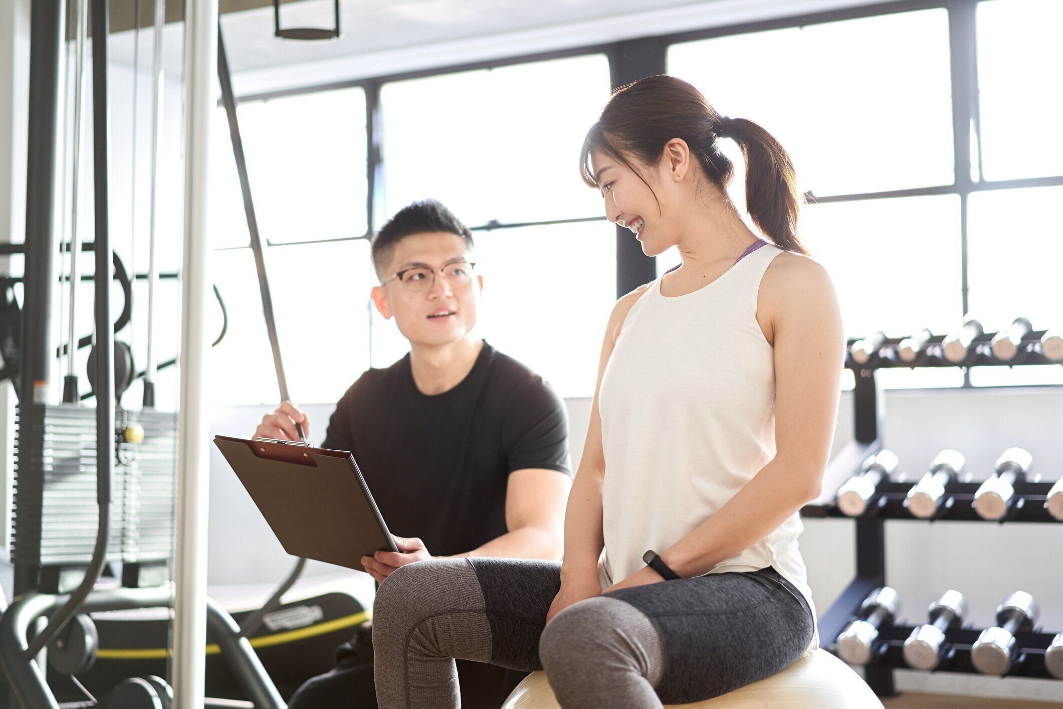 アジアの女性を教える男性パーソナルトレーナー