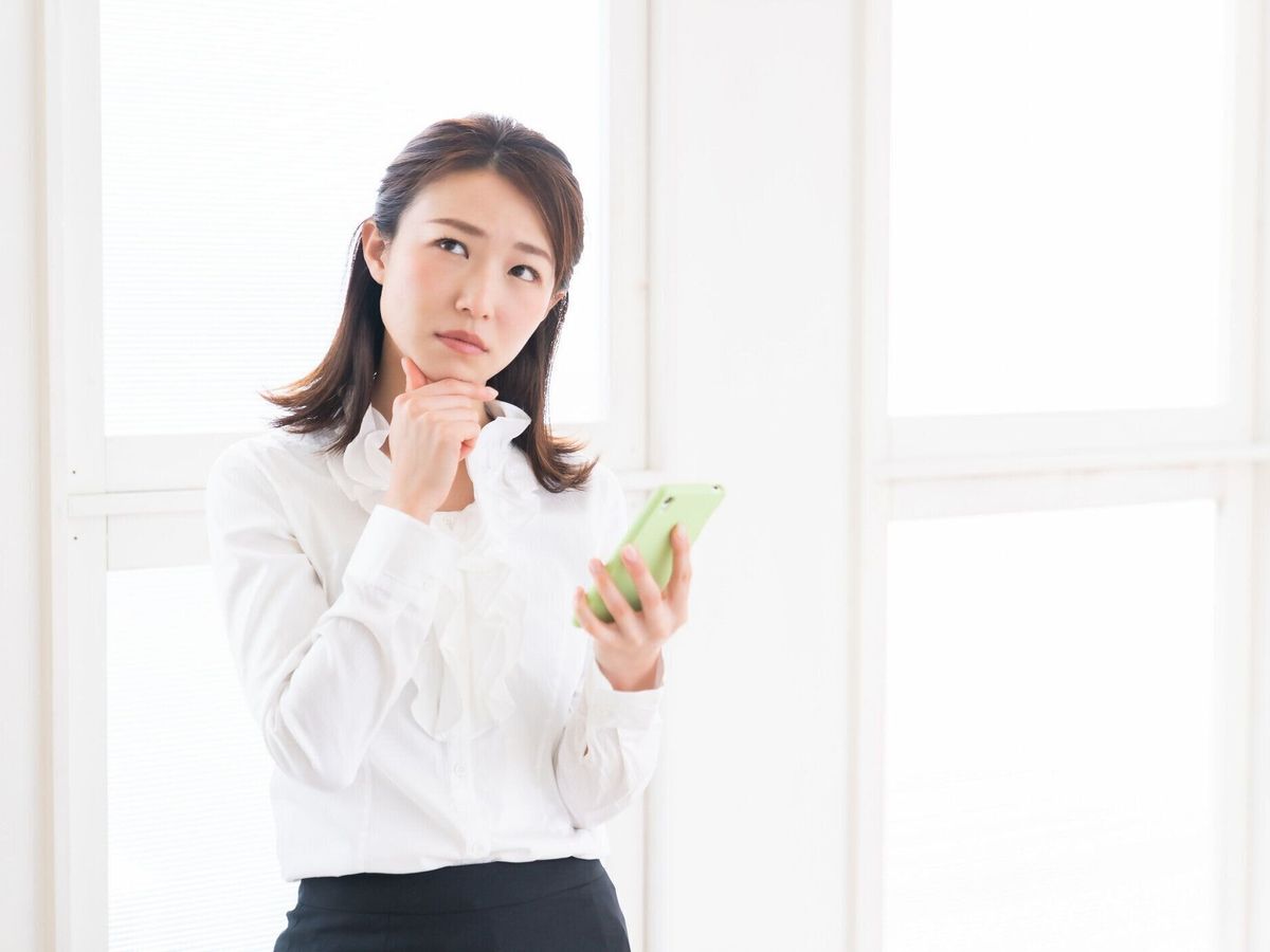 スマートフォンを見て魅力的なアジアの女性は、考える