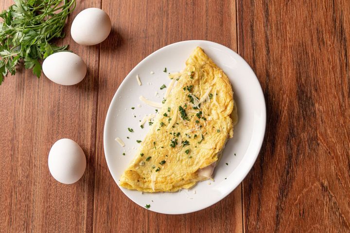 木製の背景に朝食にパセリとチーズのオムレツ。