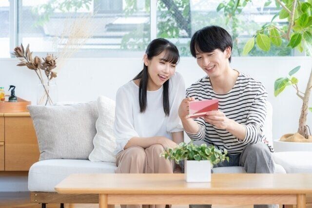 リビングで通帳を見ながら微笑むカップル