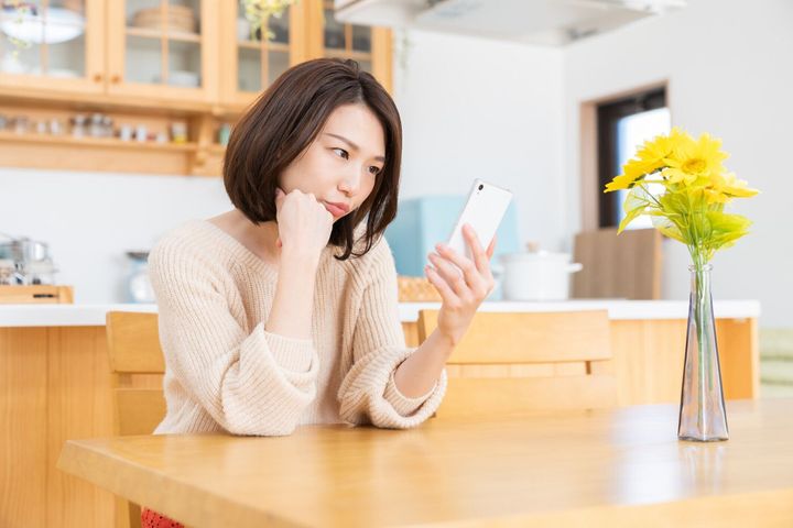 スマート フォンを見て魅力的なアジアの女性、考える、