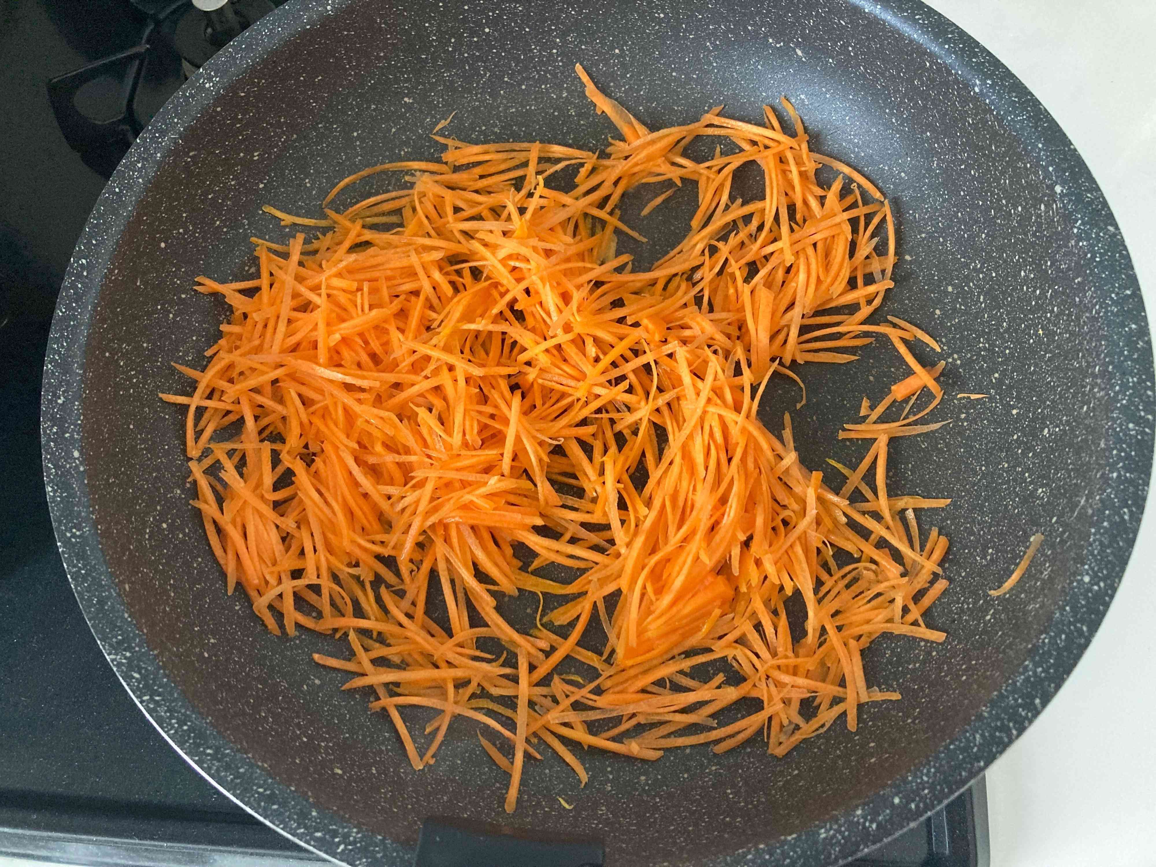 ごま油を熱したフライパンで炒めているにんじん