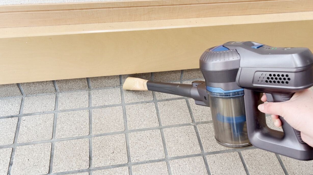掃除機で砂ぼこりを吸い取る