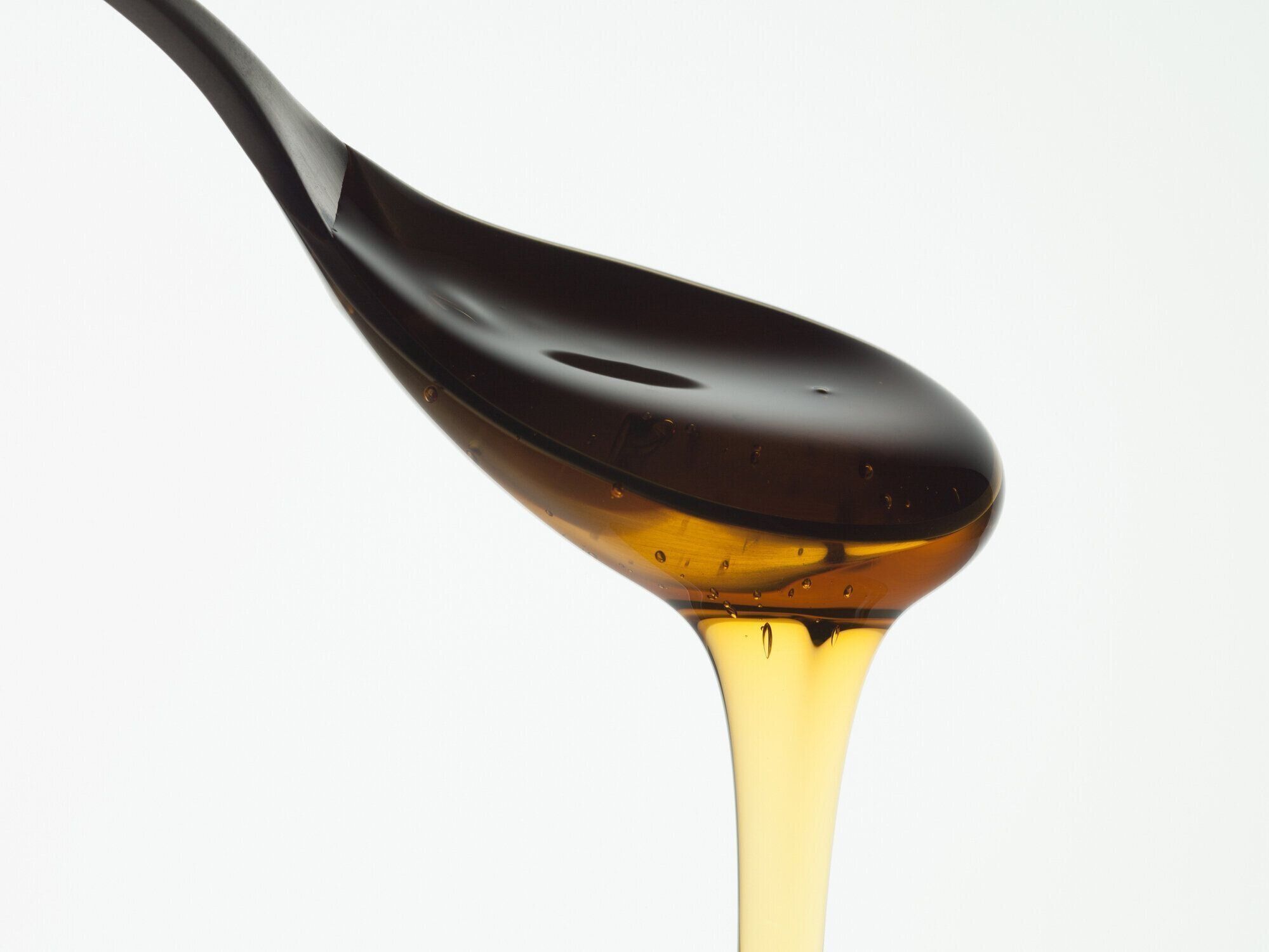 ハチミツのクローズアップのスプーンから水が滴っています。