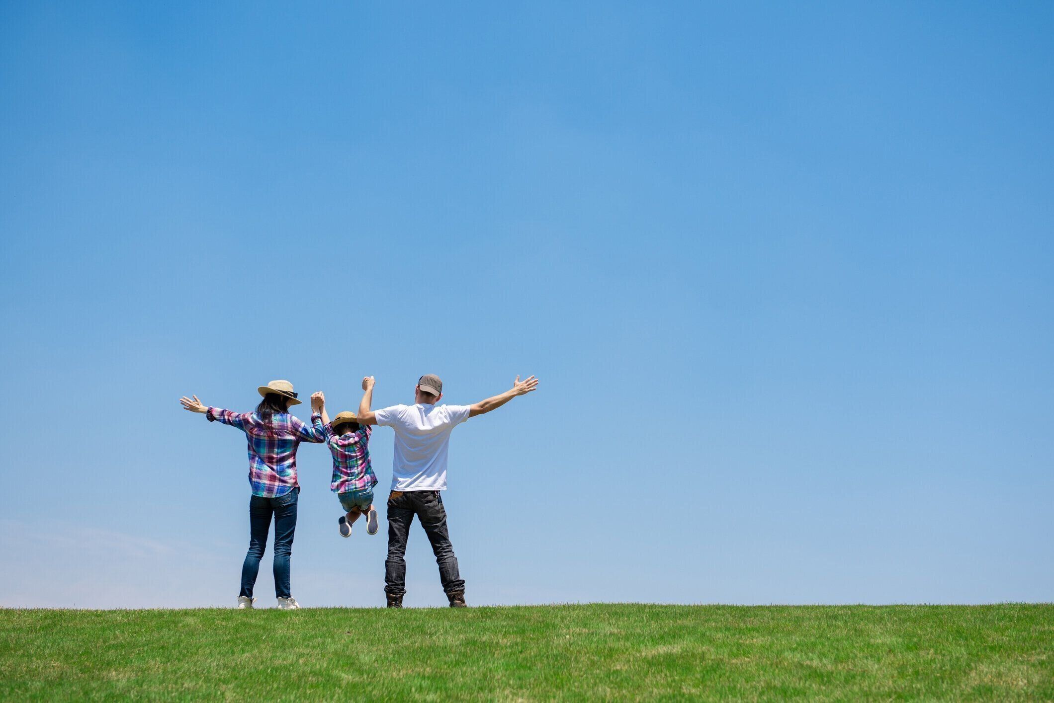牧草地で遊んでいる父と母と娘