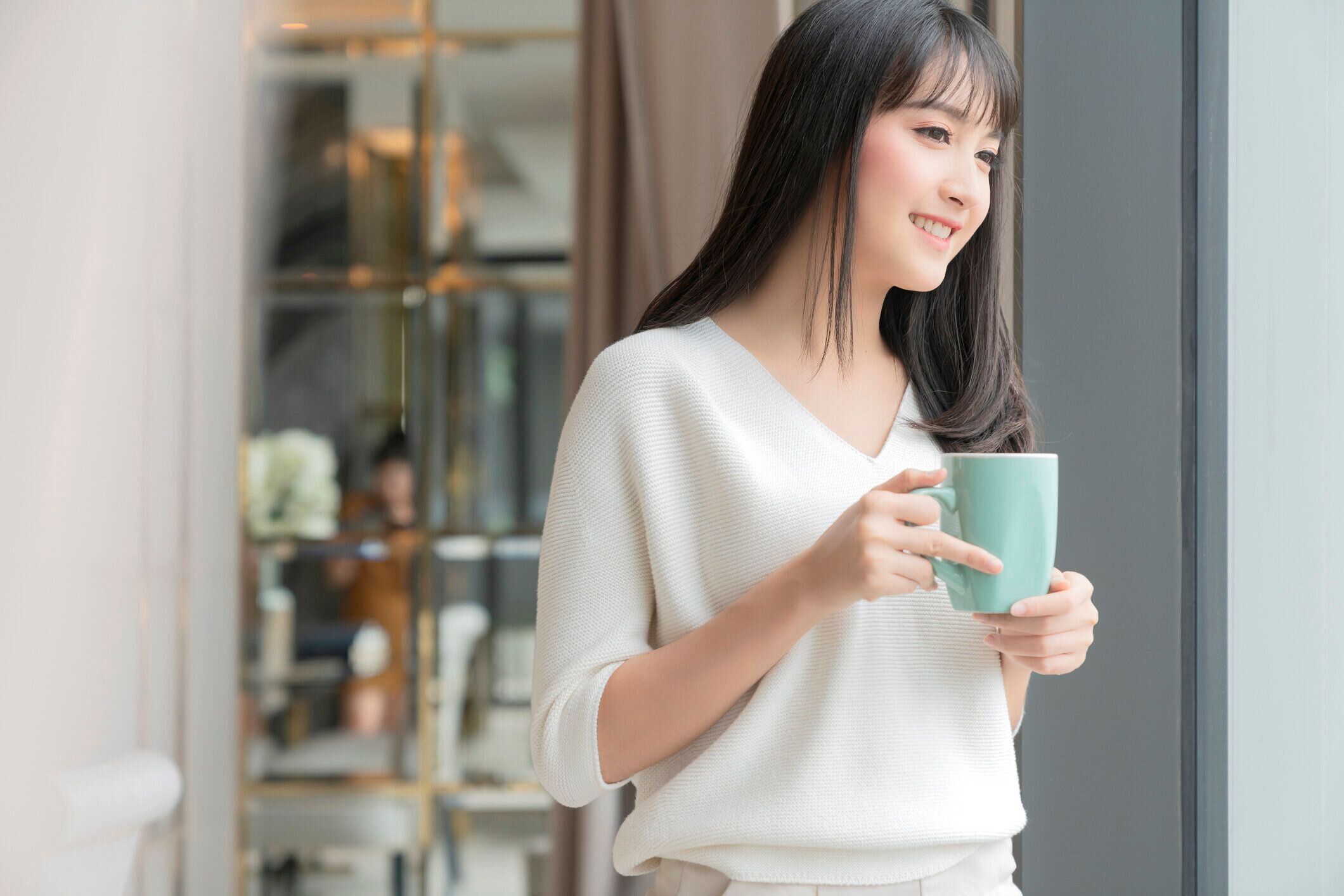 美しい魅力的なアジアの女性の新鮮さは幸せと自宅からラップトップコーヒーワークで働いて陽気な朝笑顔、庭の景色を楽しむ、窓の明るい庭の背景を持つアジアの若い女性