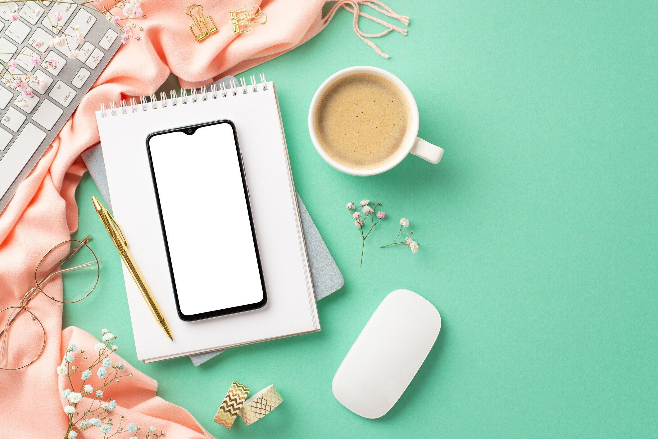ビジネスコンセプト。スマートフォンのコピーブックのトップビュー写真キーボードコンピューターのマウスマグカップコーヒー金色の文房具メガネ、カスミソフィラの花とピンクのスカー�