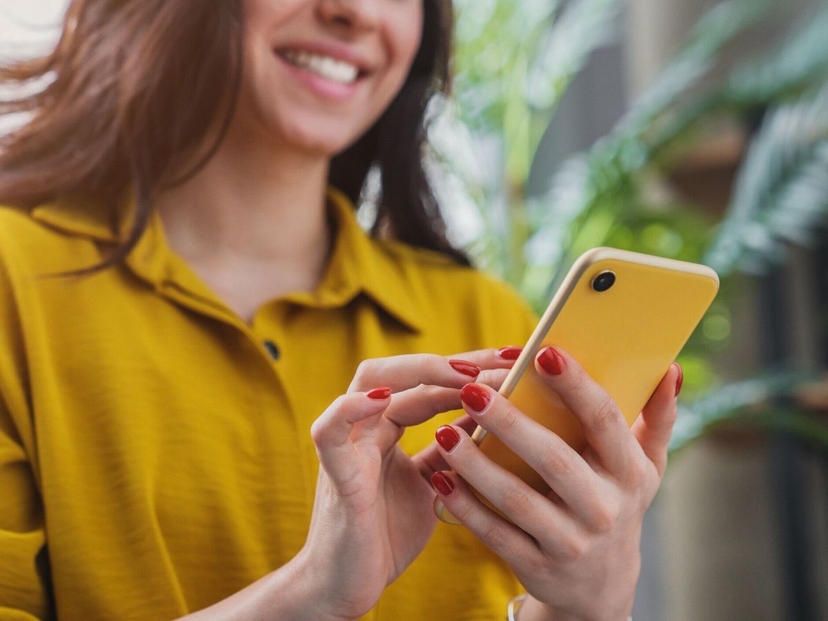 自宅で寒い間、スマートフォンのデバイスを使用して幸せな女の子のトリミング画像