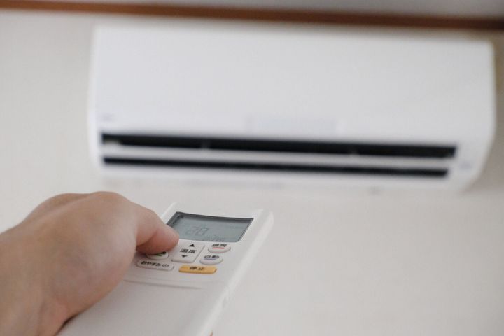 リモコンを手に持ったエアコンを操作するイメージ