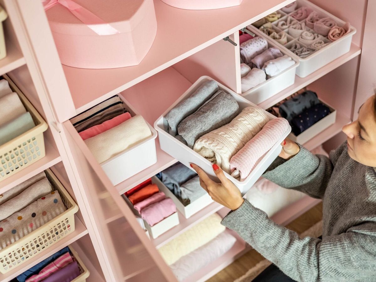 女性の子供のワードローブクローゼットで片付けを楽しむ幸せな若い母親はきちんと折りたたまれた服