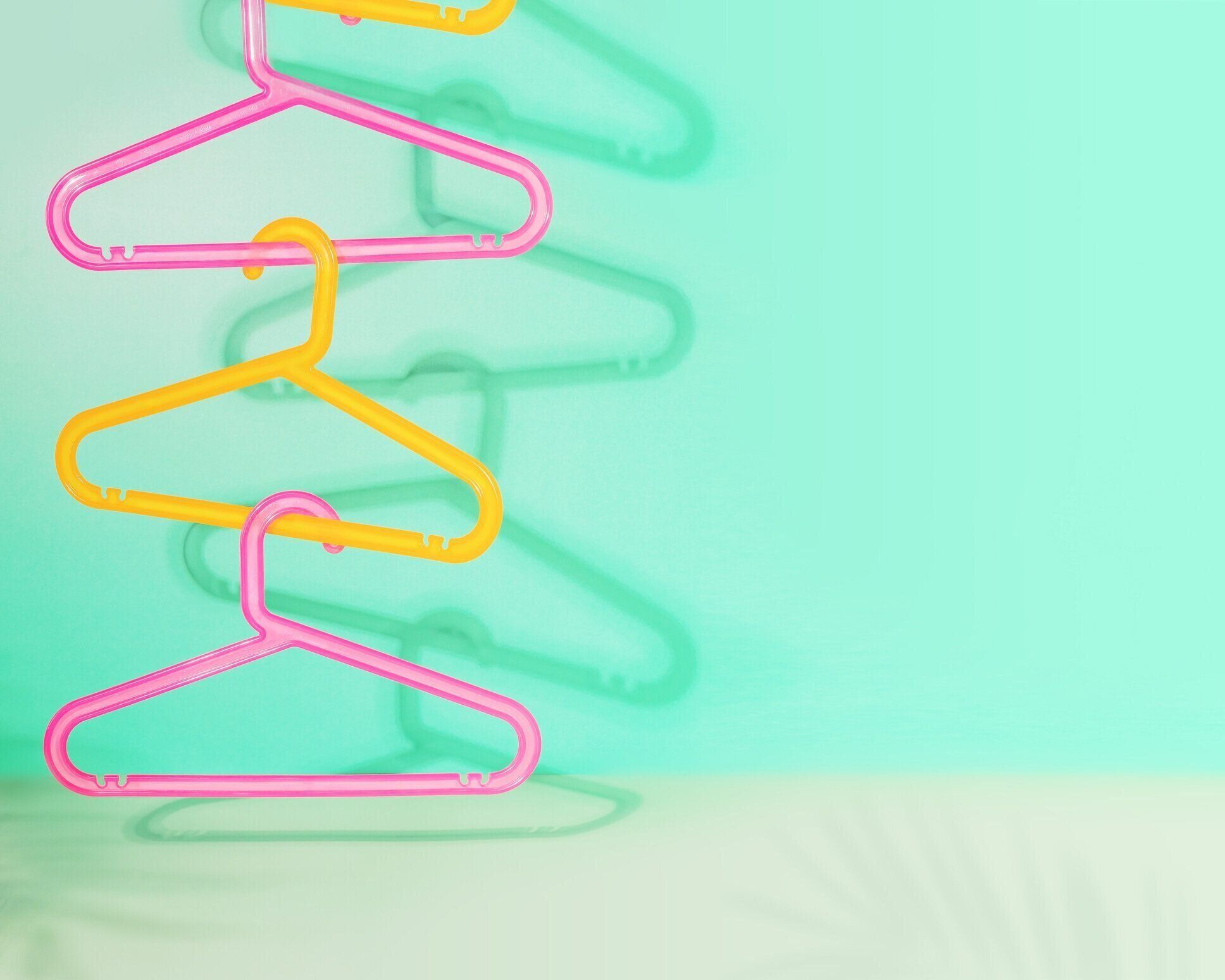 影のあるミントの背景に色付きのプラスチックハンガーを持つ販売構成