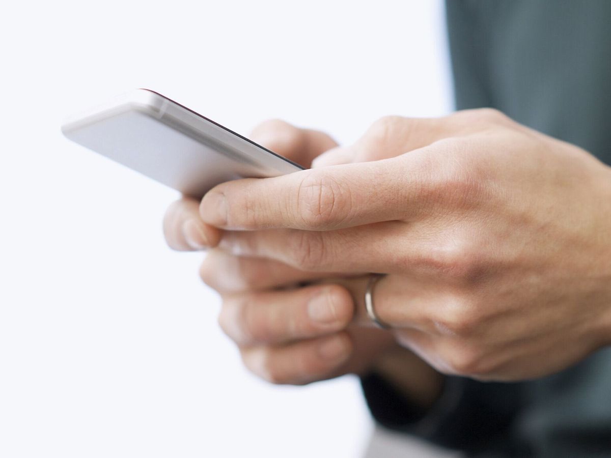 スマートフォンでテキストを入力するアジア人男性