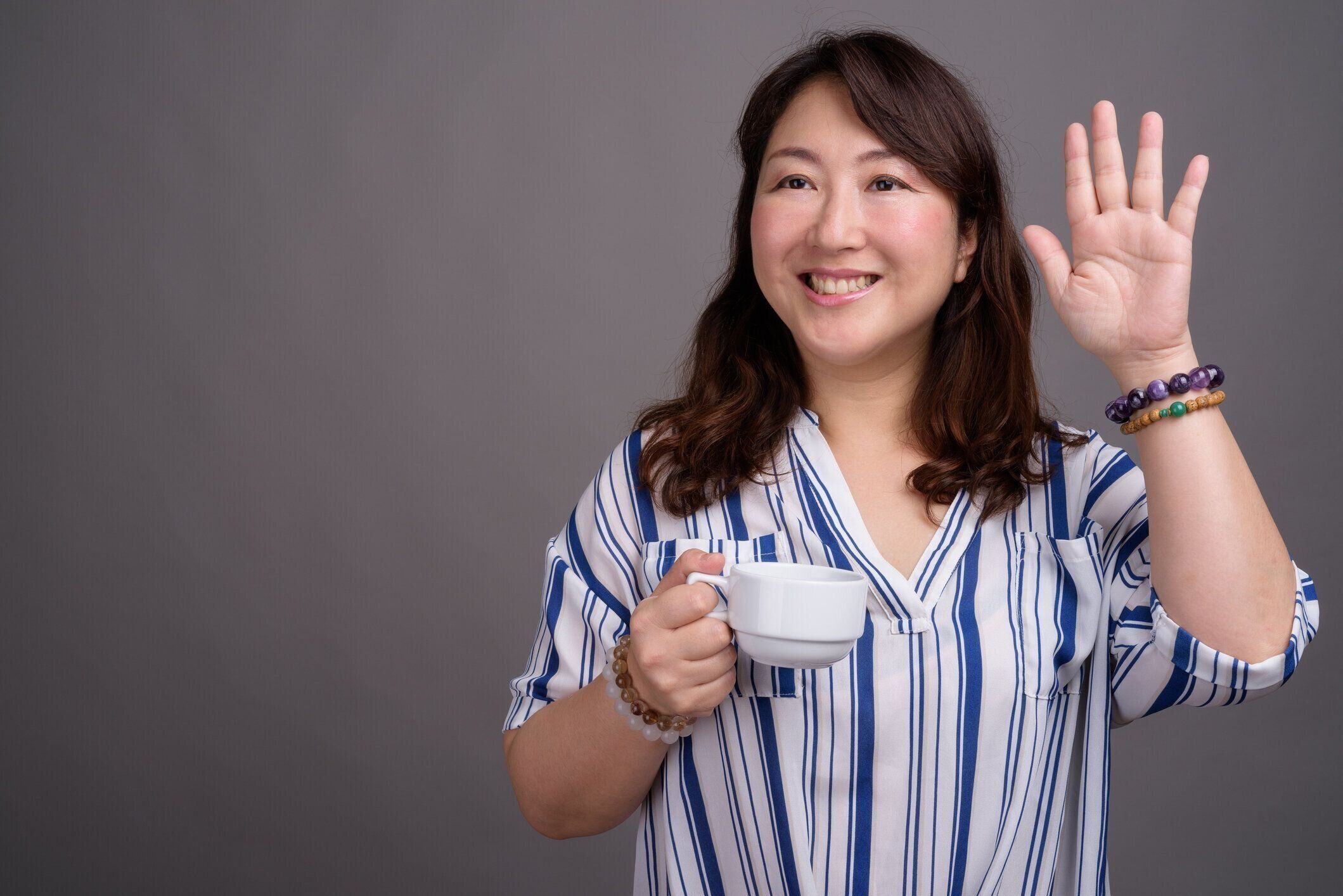 灰色の背景の成熟した美しいアジア女性実業家のスタジオ撮影