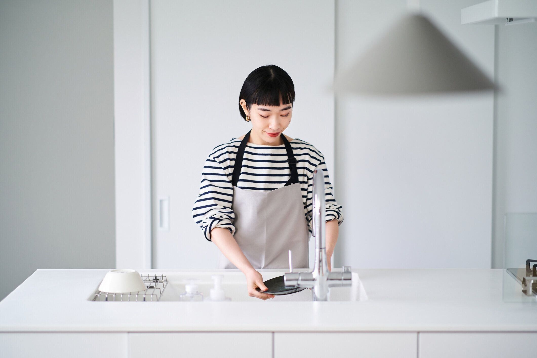 台所で皿洗いをする女性