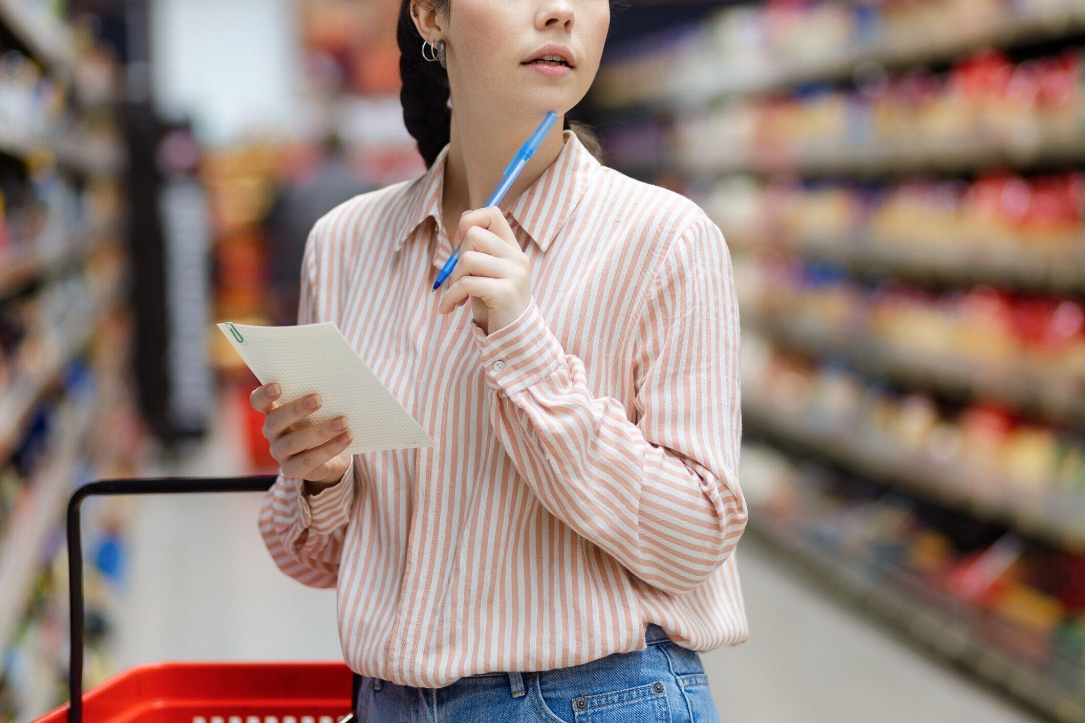 ショッピングのコンセプト。スーパーマーケットで食料品を選ぶ若い白人女性の接写。背景には、製品のある棚の列