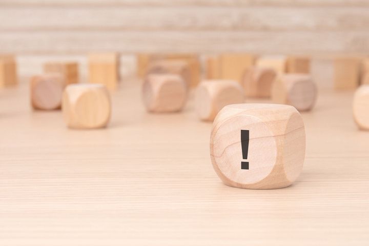 茶色の背景に側面に黒の感嘆符が付いた小さな木製のブロック