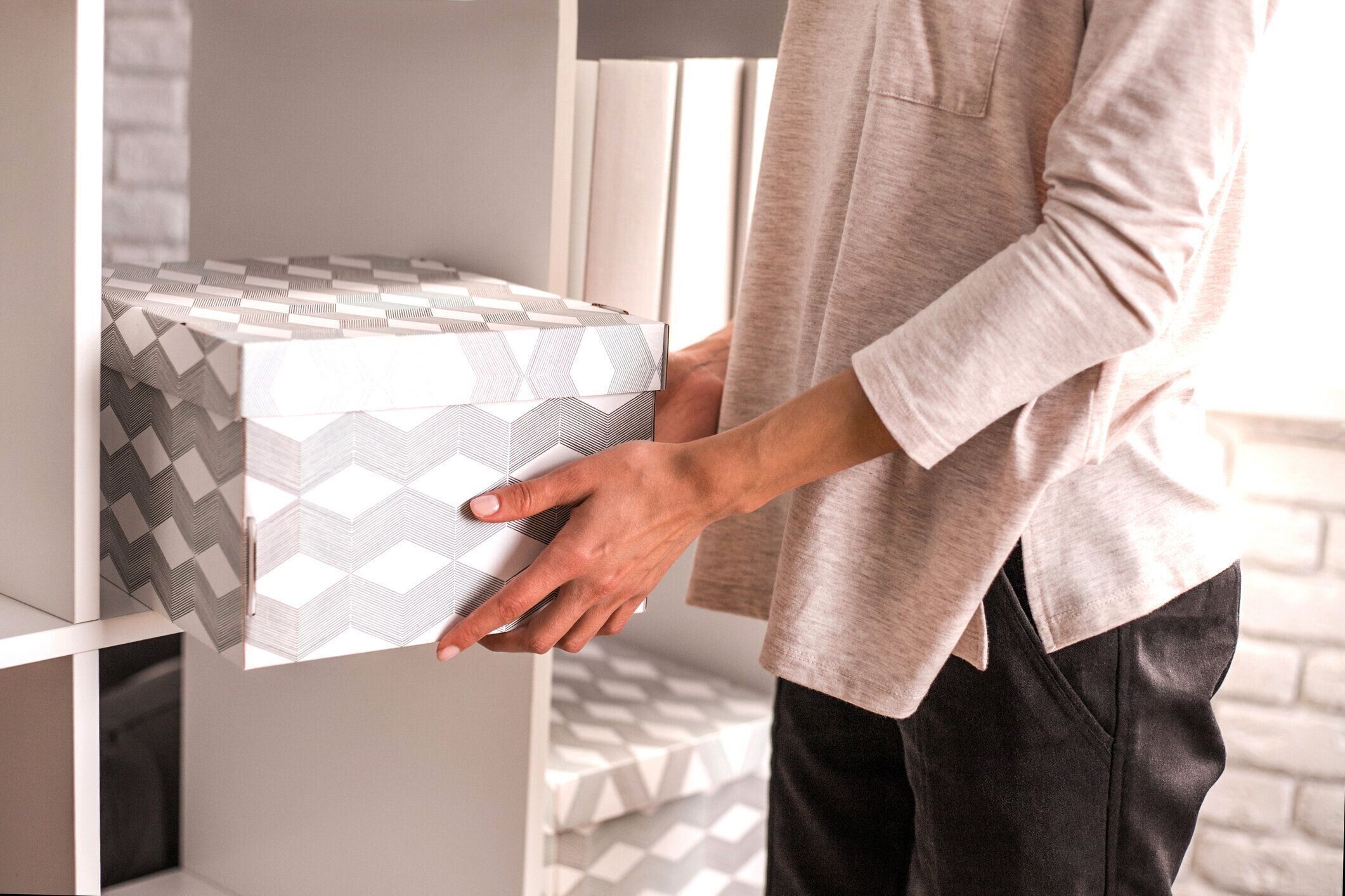 女性は、棚の上の段ボール箱を配置しました。