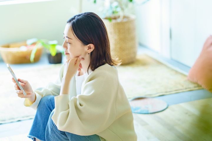 部屋でスマホを持っている女性
