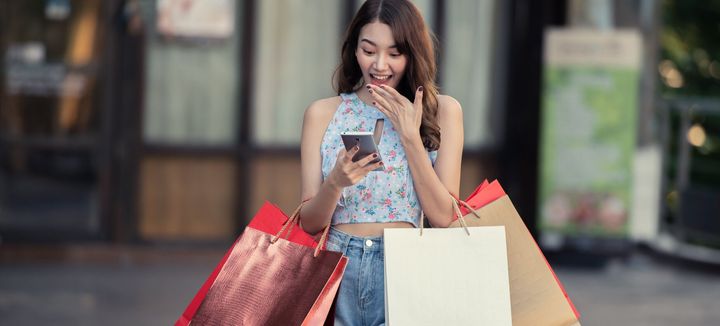 携帯電話を持つ若いショッピングの女性。